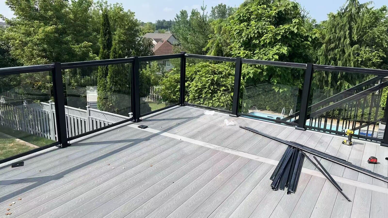 Rooftop composite deck with glass railing overlooking a treed yard