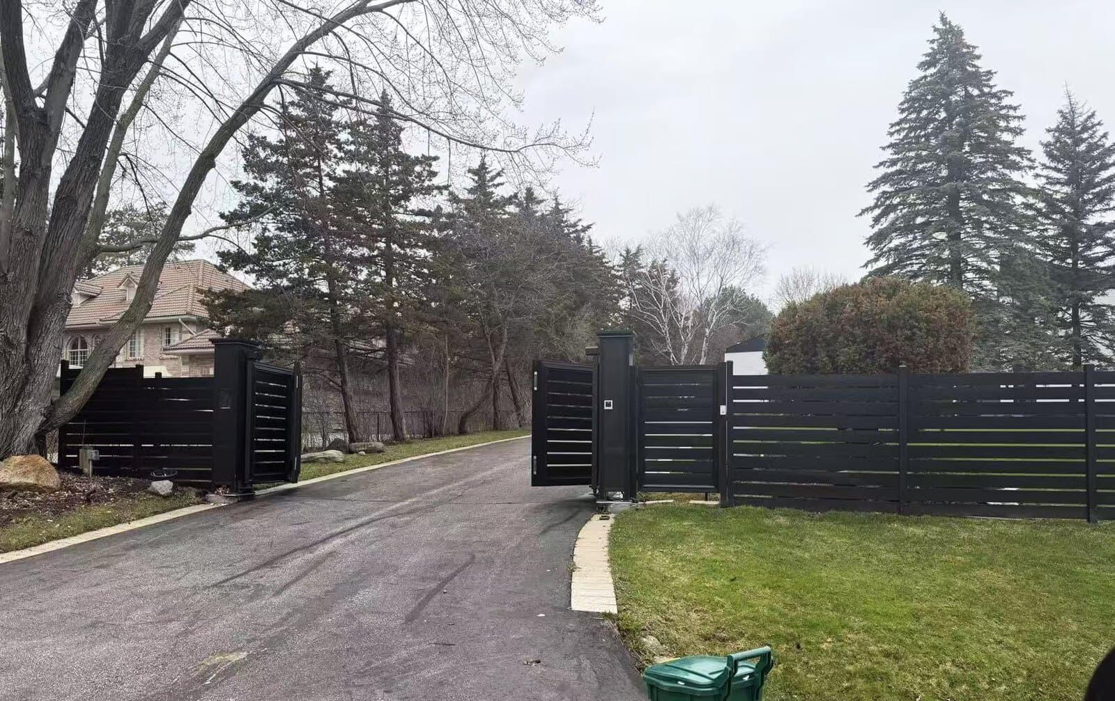 Aluminum driveway gates matched to a horizontal-slat fence line