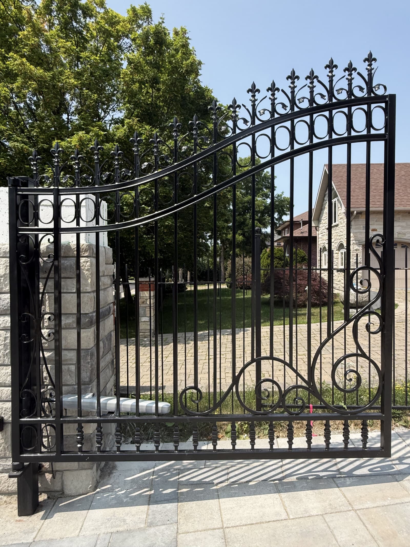 Custom wrought-iron gate with scrollwork and fleur-de-lis finials