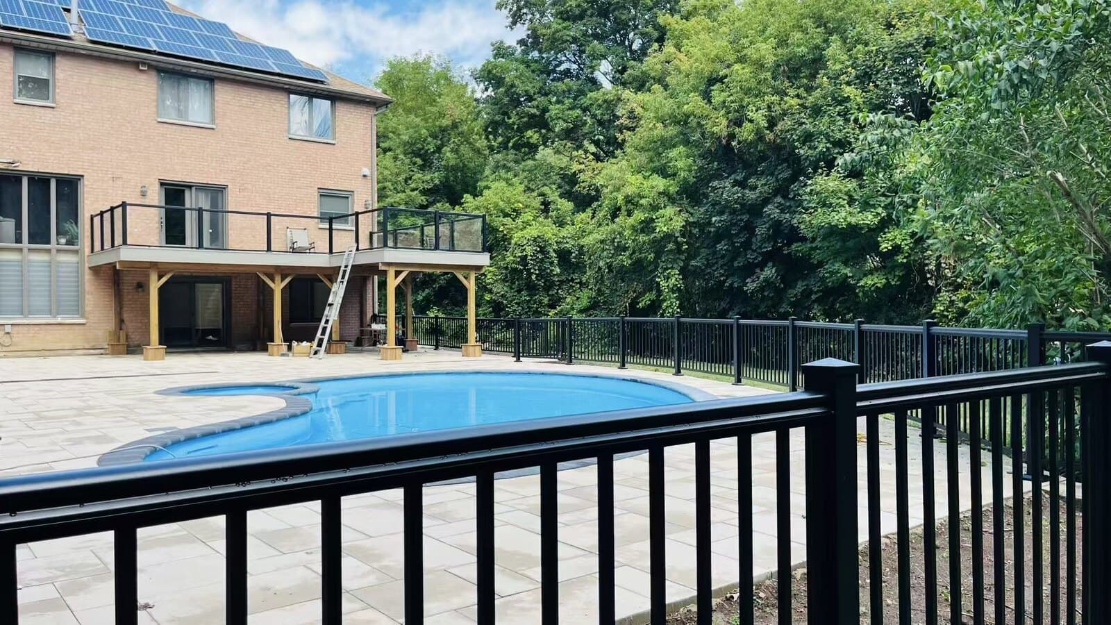 Black aluminum pool fence with a pressure-treated wood deck behind