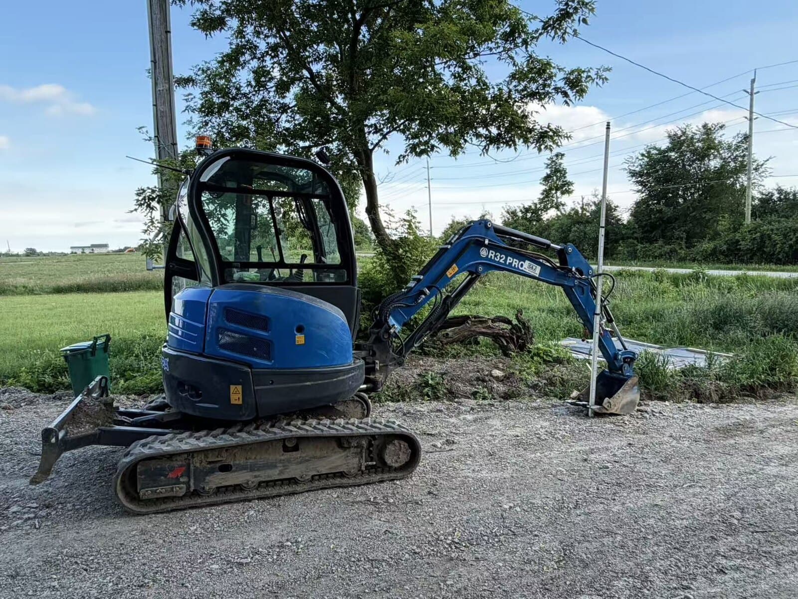 Compact tracked excavator parked beside a field