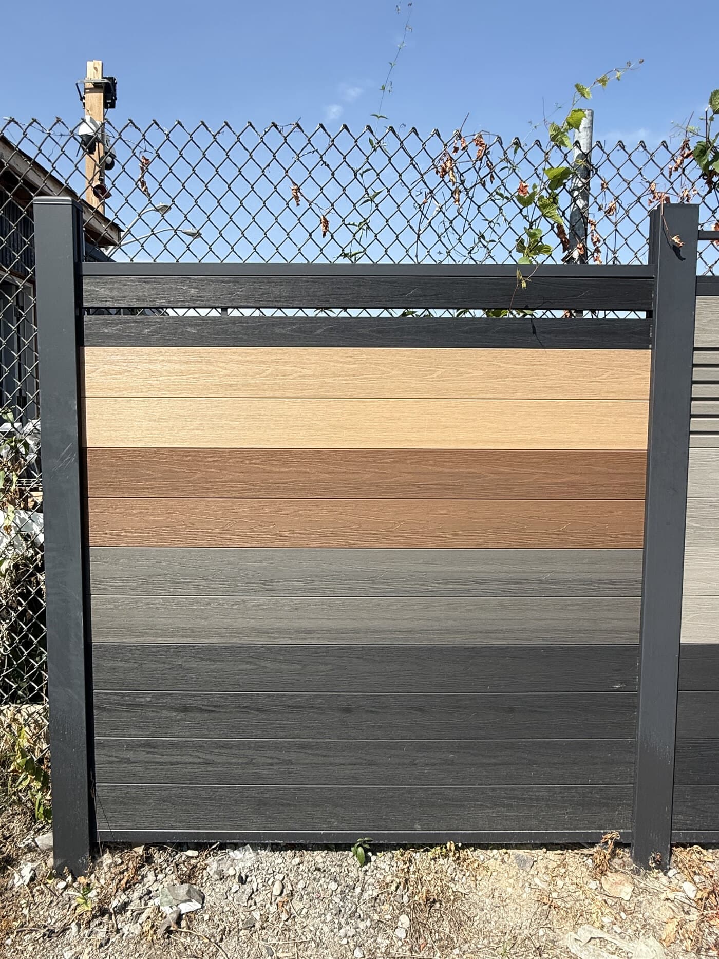 WPC fence display panel mixing teak, walnut, and grey boards in an aluminum frame