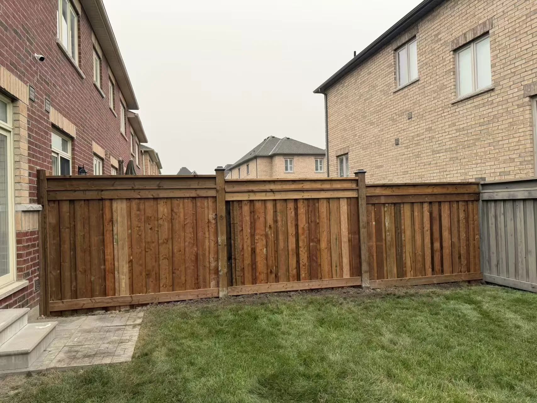 Completed pressure-treated wood fence enclosing a residential backyard