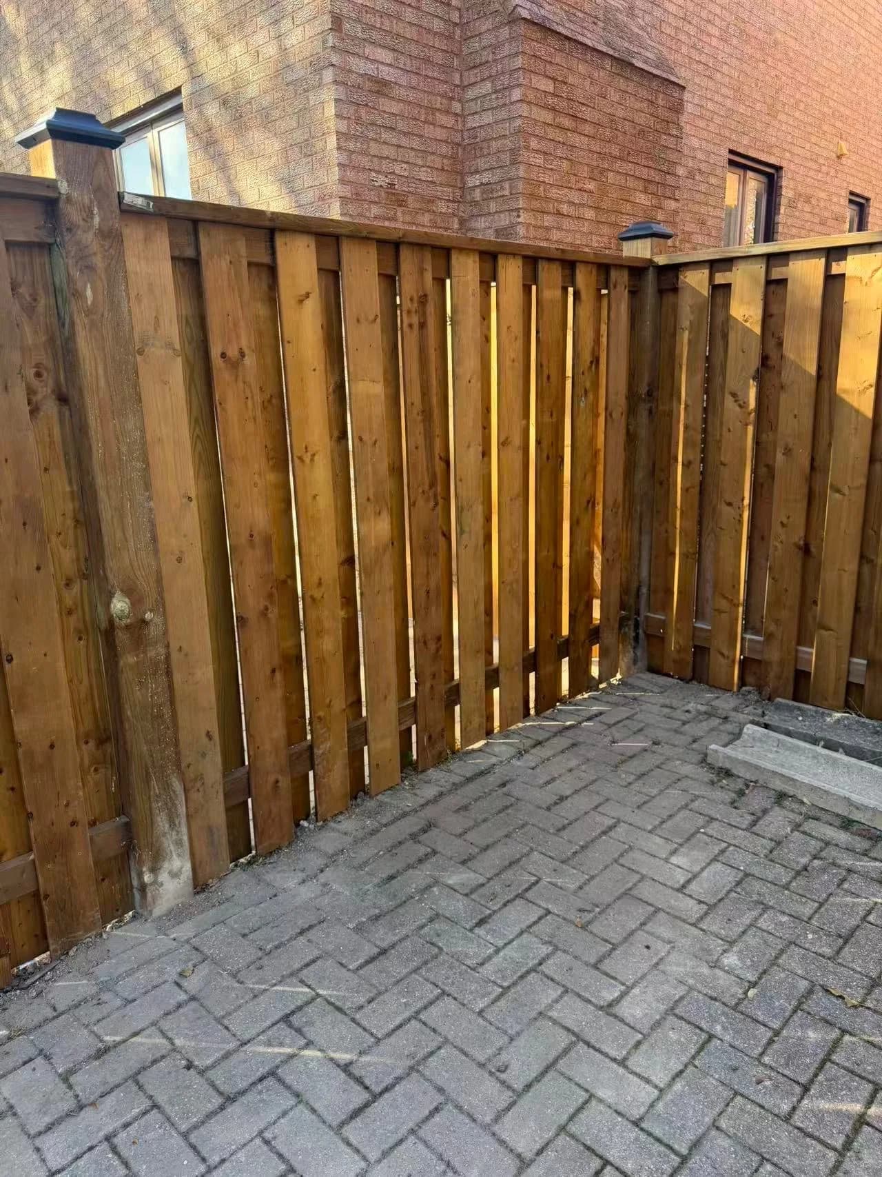Pressure-treated wood fence turning a corner beside a brick home
