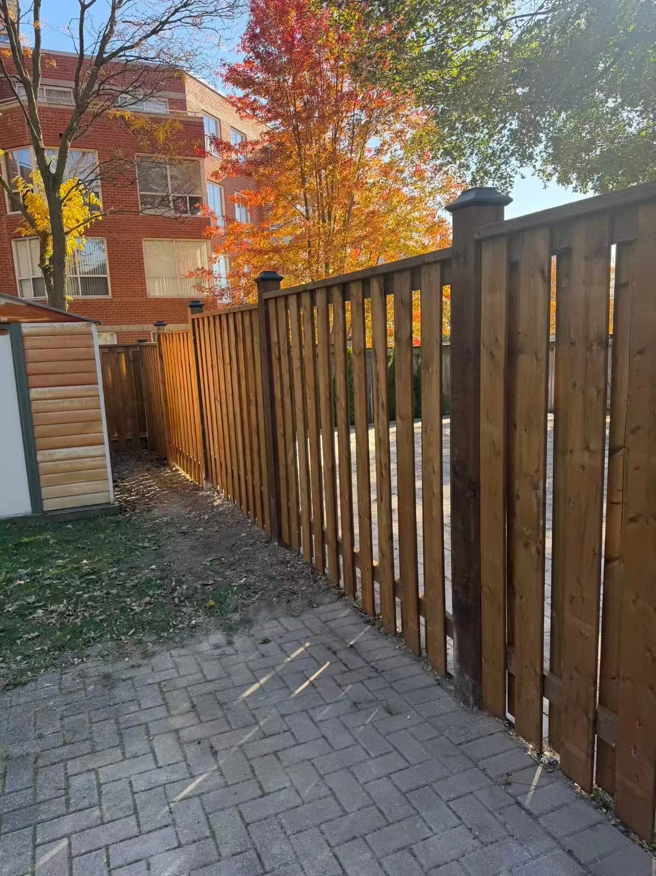 Pressure-treated wood fence running along an interlock patio with solar post caps