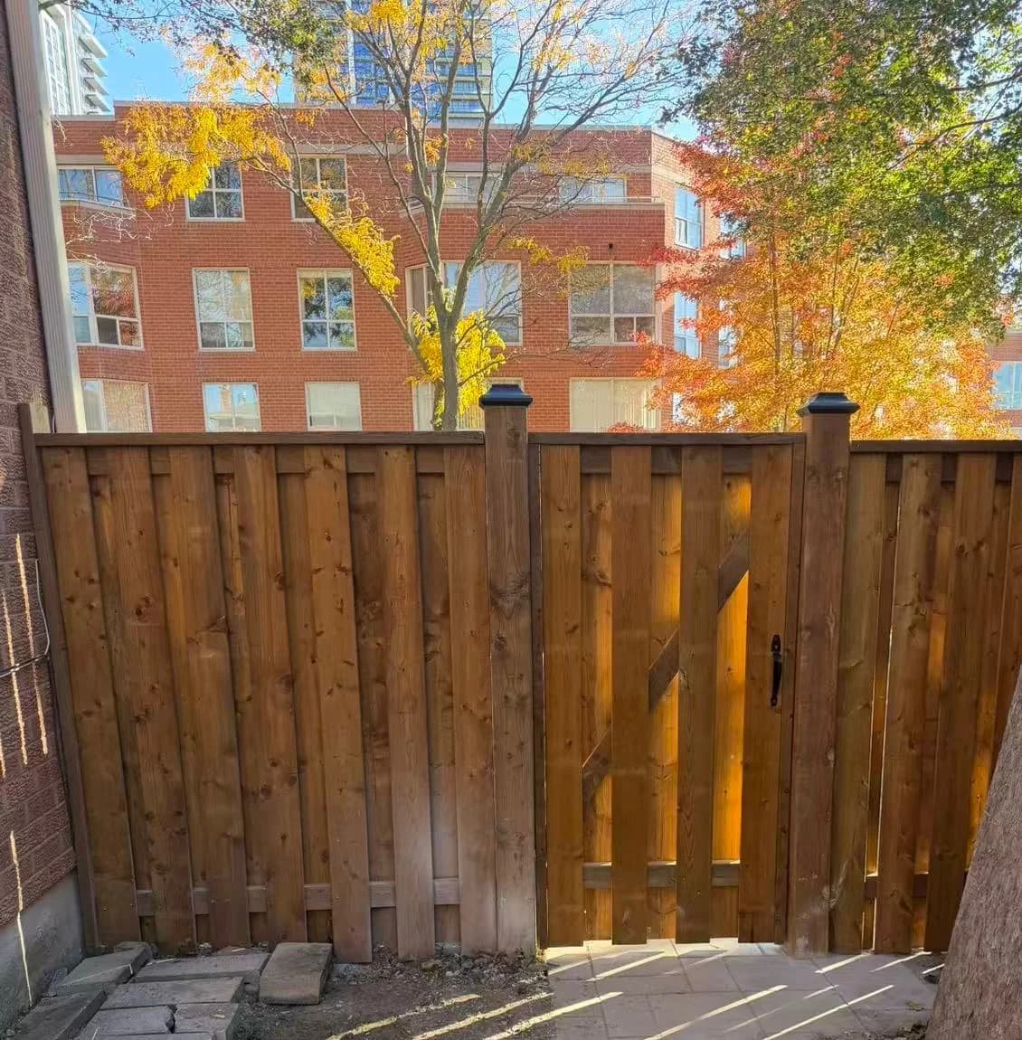 Pressure-treated wood side-yard fence with a matching braced gate and black solar post caps