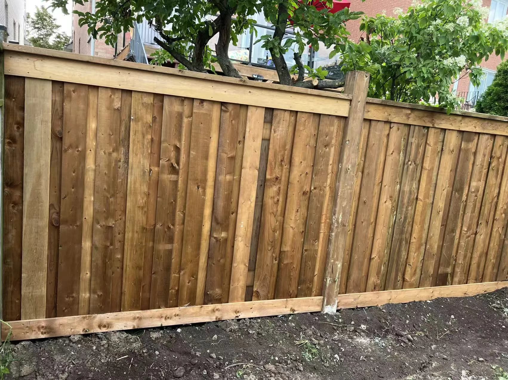 Wide view of a completed pressure-treated wood privacy fence