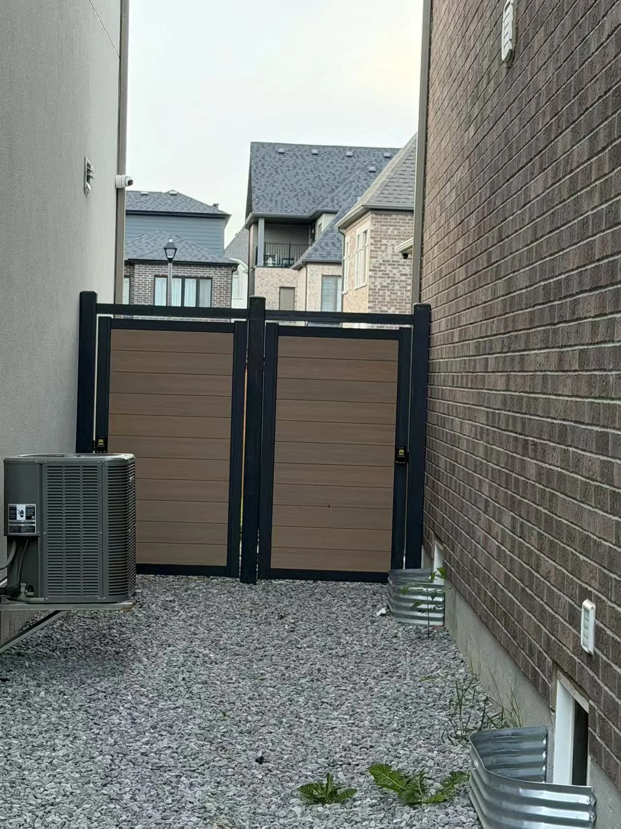 Brown WPC side-yard fence panels in black metal frames